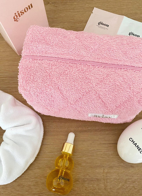 Pink terrycloth pouch with textured fabric and top zipper, small label patch on front.