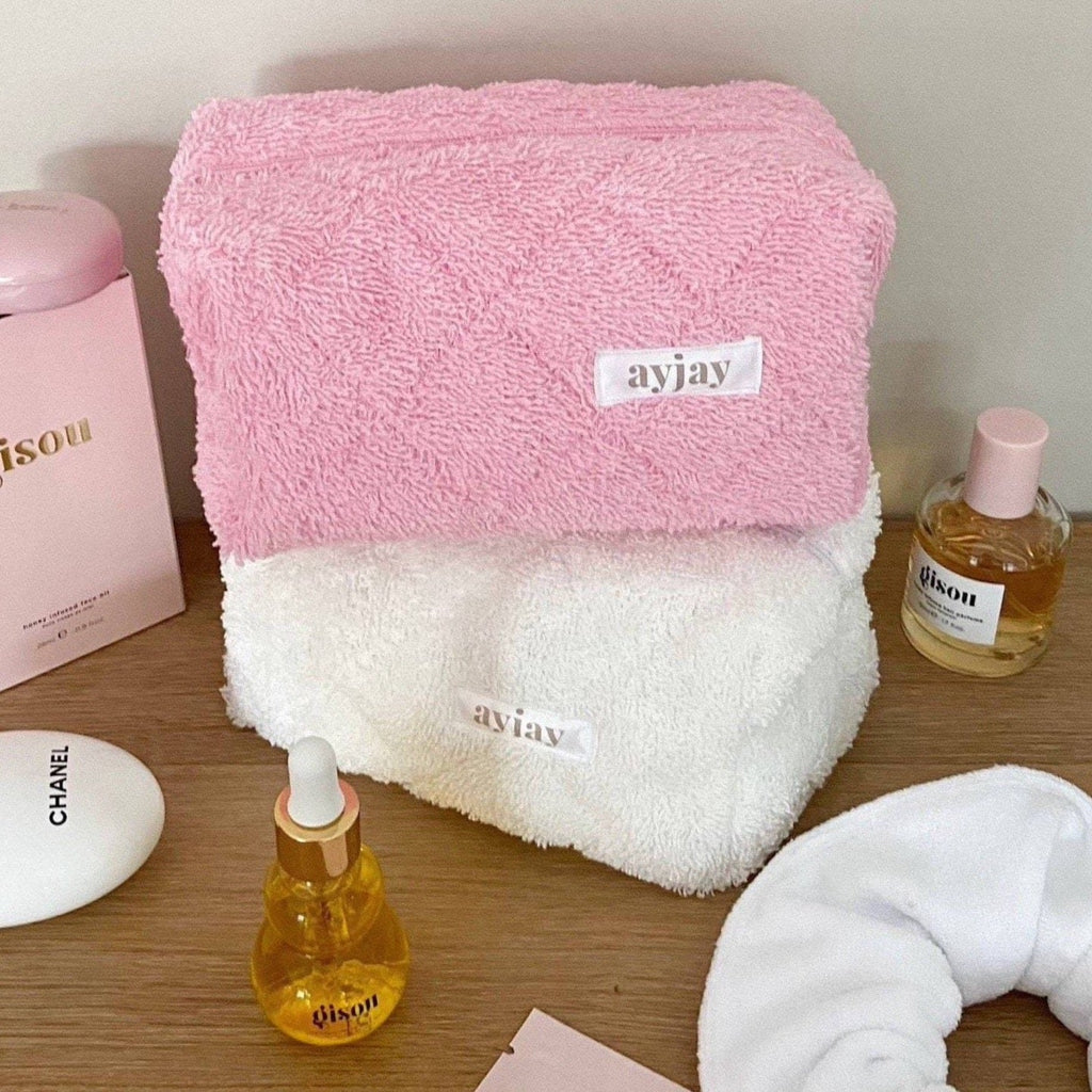 Pink and white terrycloth pouch set, pink pouch on top with label patch and zipper.