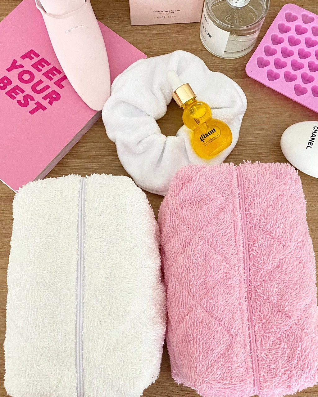 Pink terrycloth zip pouch next to a white towel pouch, both with visible fabric texture.