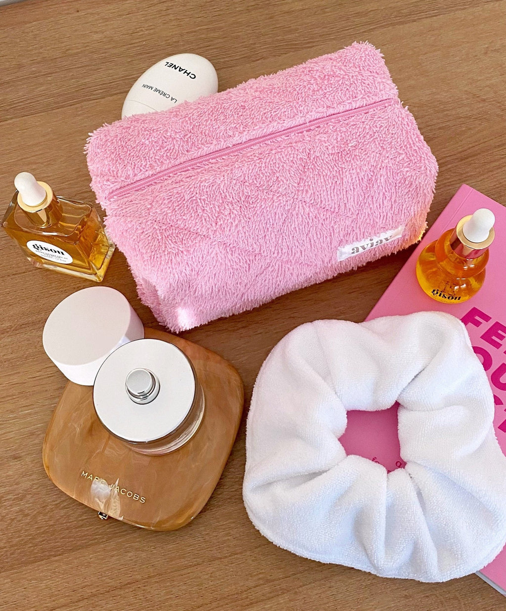 Pink rectangular terrycloth pouch with zipper and sewn label, shown with fabric texture detail.