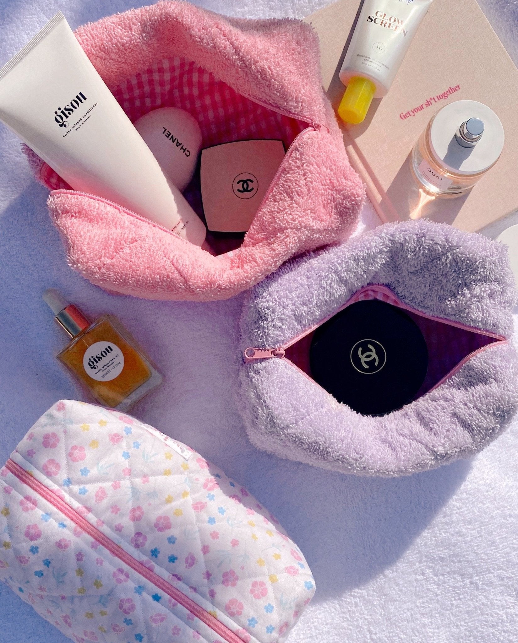Lavender and pink terrycloth zip pouches with zippers open, showing lining and logo patch