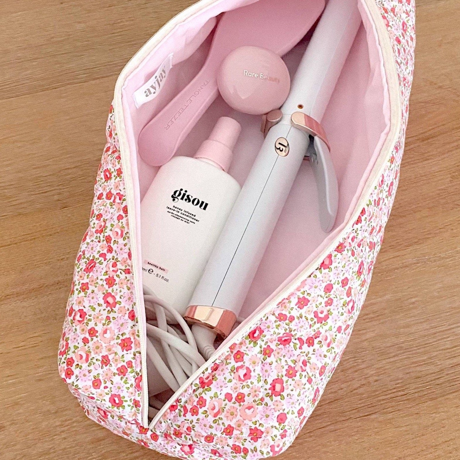 Floral zip pouch open, showing pink-and-white tools and bottles inside