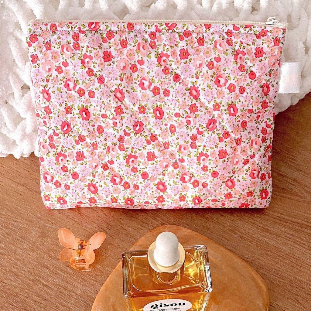 Floral zip pouch front view, with scattered beauty items nearby