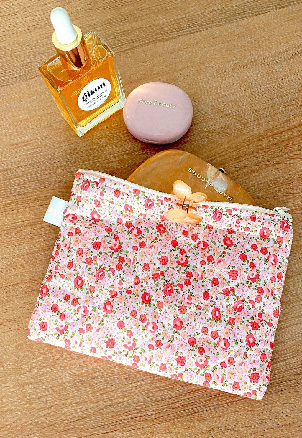 Floral zip pouch with zipper pull, flat pouch lying on a wood surface