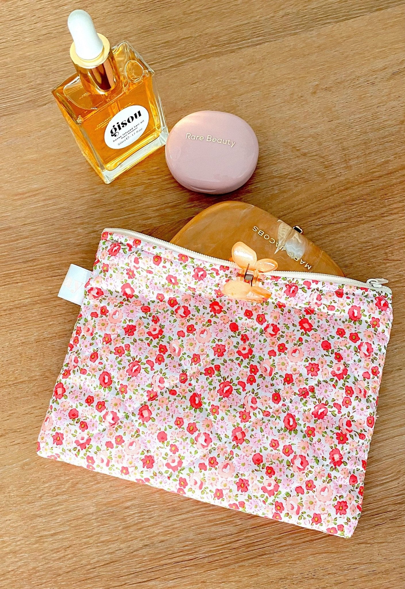 Floral zip pouch with zipper pull, flat pouch lying on a wood surface
