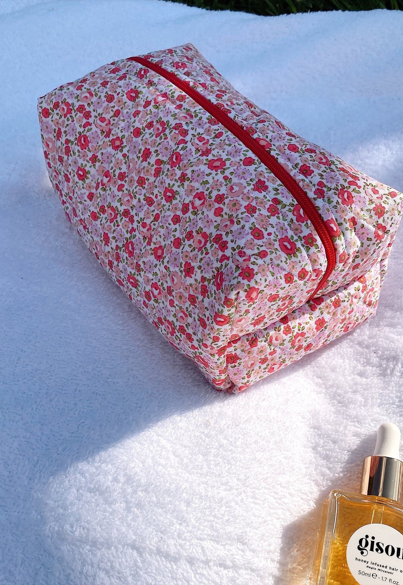 Pink floral zip pouch with red trim and pink gingham lining, side view