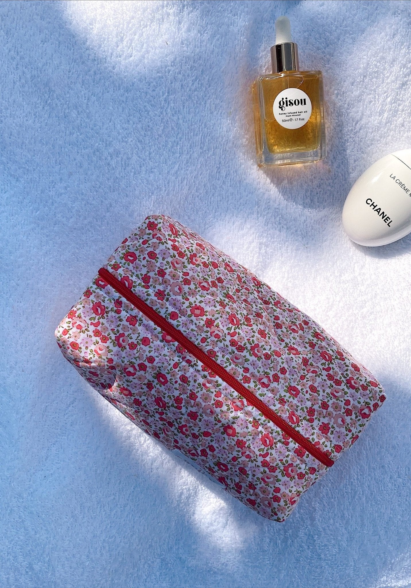 Rectangular floral cosmetic pouch with red zipper and pink gingham lining, closed
