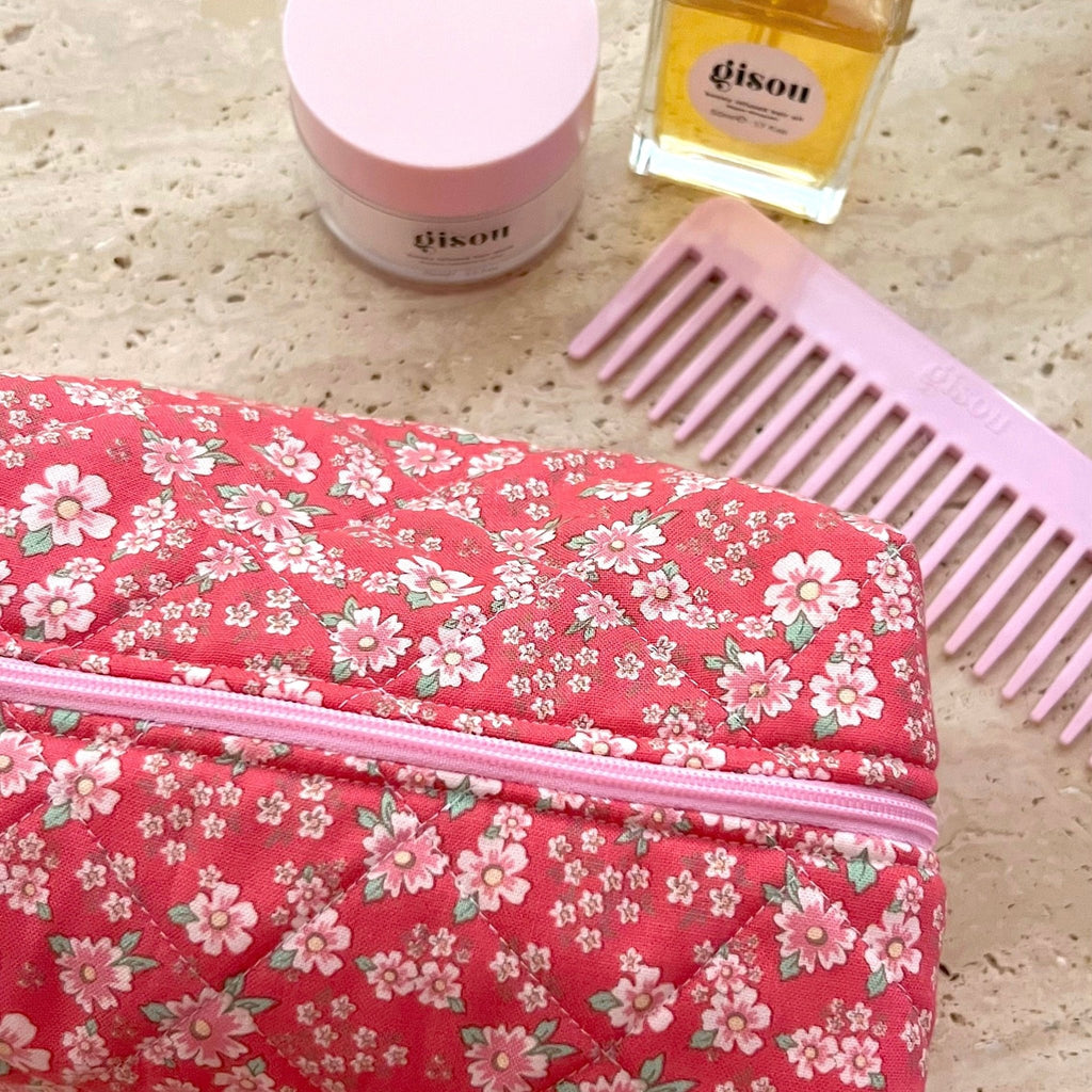 Red floral fabric pouch with pink zipper stripe, close-up view