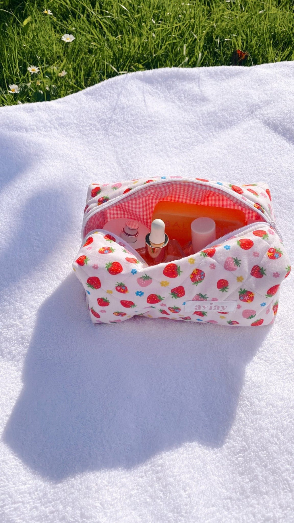 Strawberry floral zip pouch opened, red gingham lining visible inside