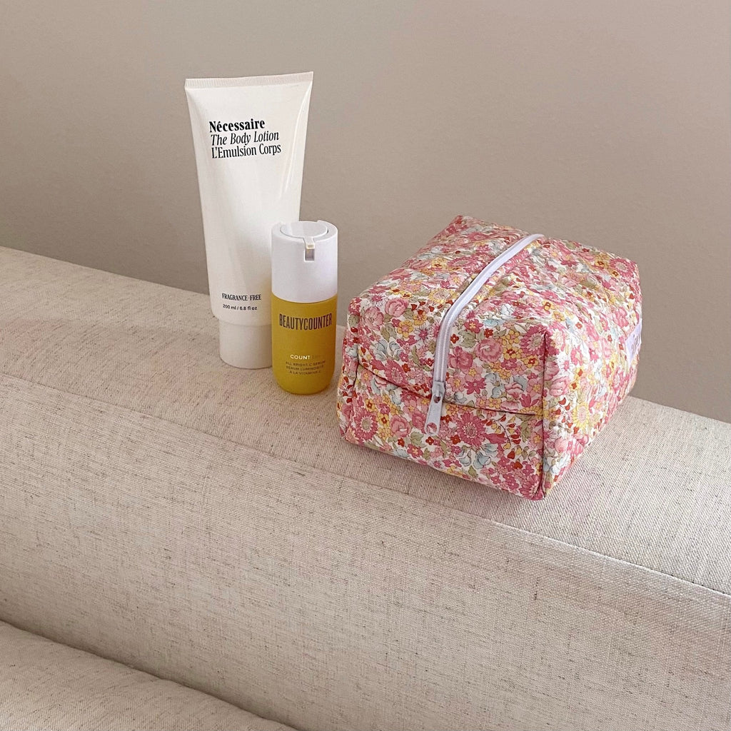 Floral travel pouch with zipper and top handle, folded on sofa