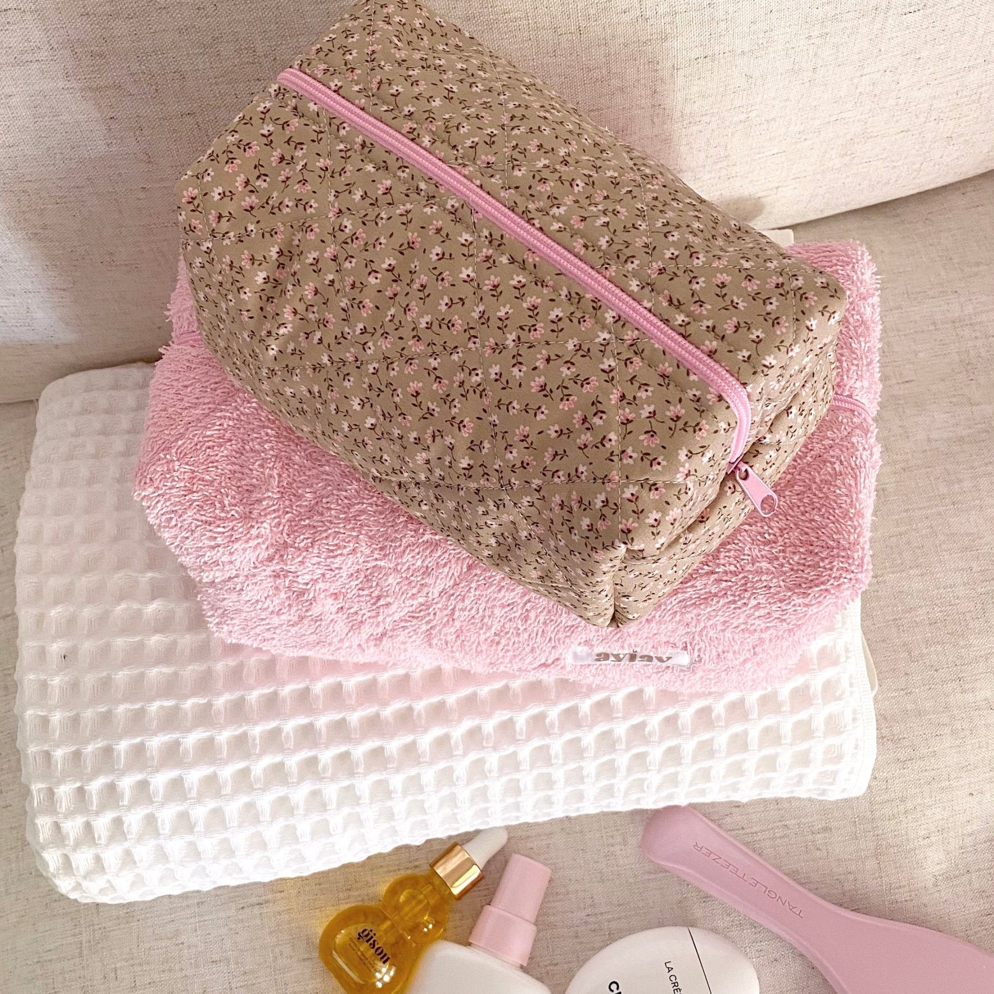 Tan ditsy floral pouch with pink zipper, angled view showing textured fabric exterior