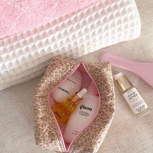 Ditsy floral toiletry bag with pink trim and zipper, open top pouch with bottles inside