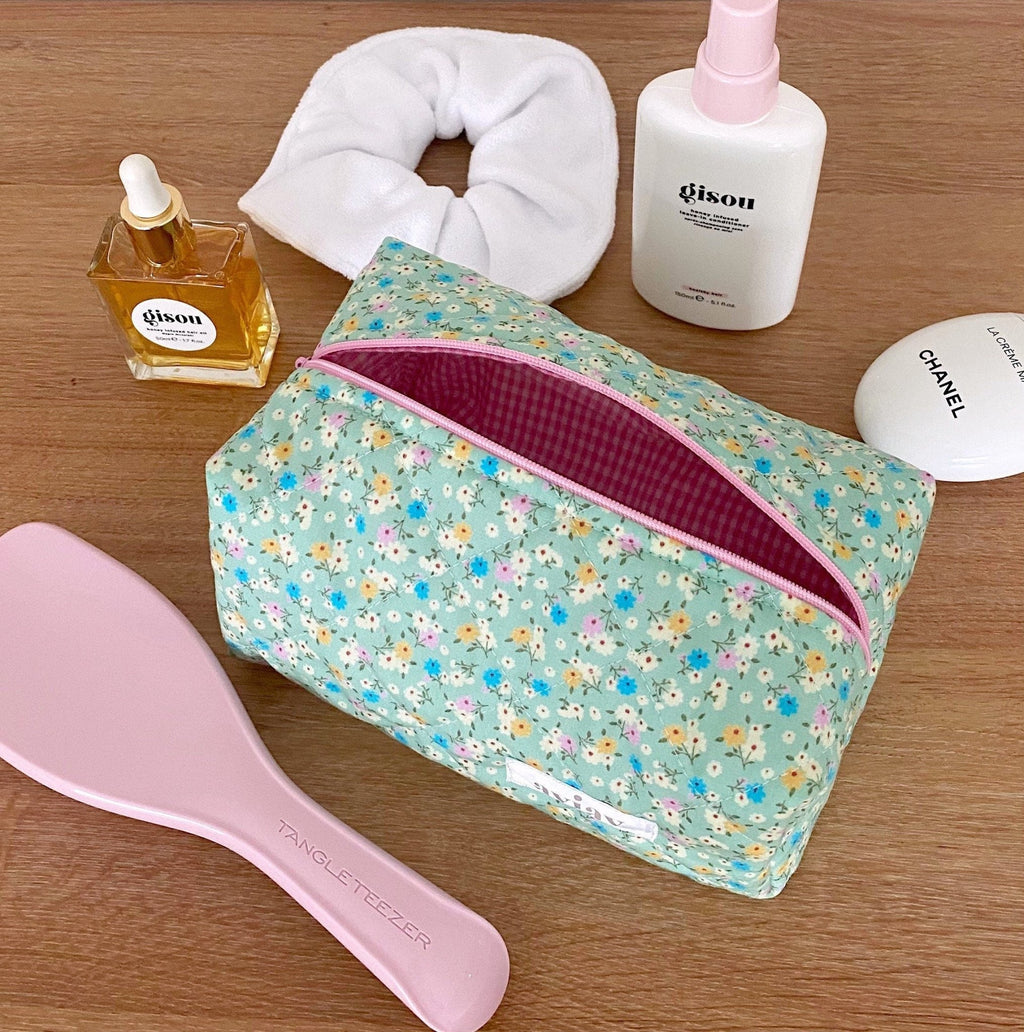 Floral toiletry pouch in light teal with multicolor blossoms and magenta-lined zipper