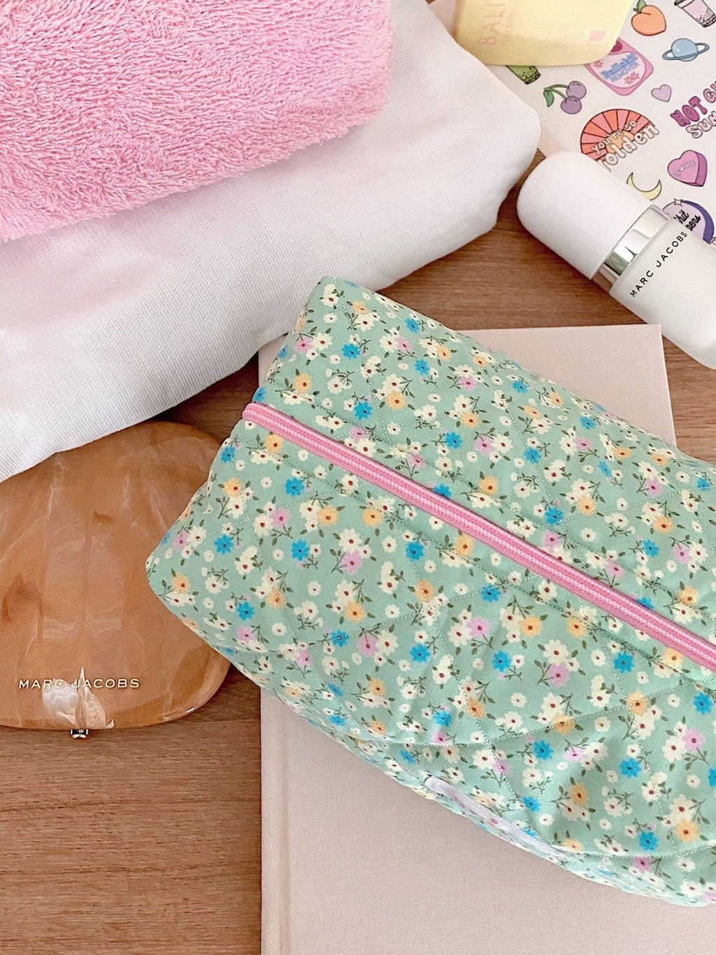 Close-up of floral zip pouch in light teal with pink zipper and multicolor flowers