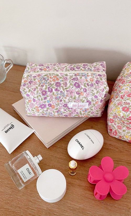 Purple floral cosmetic pouch with zipper pocket on wooden surface, printed logo front