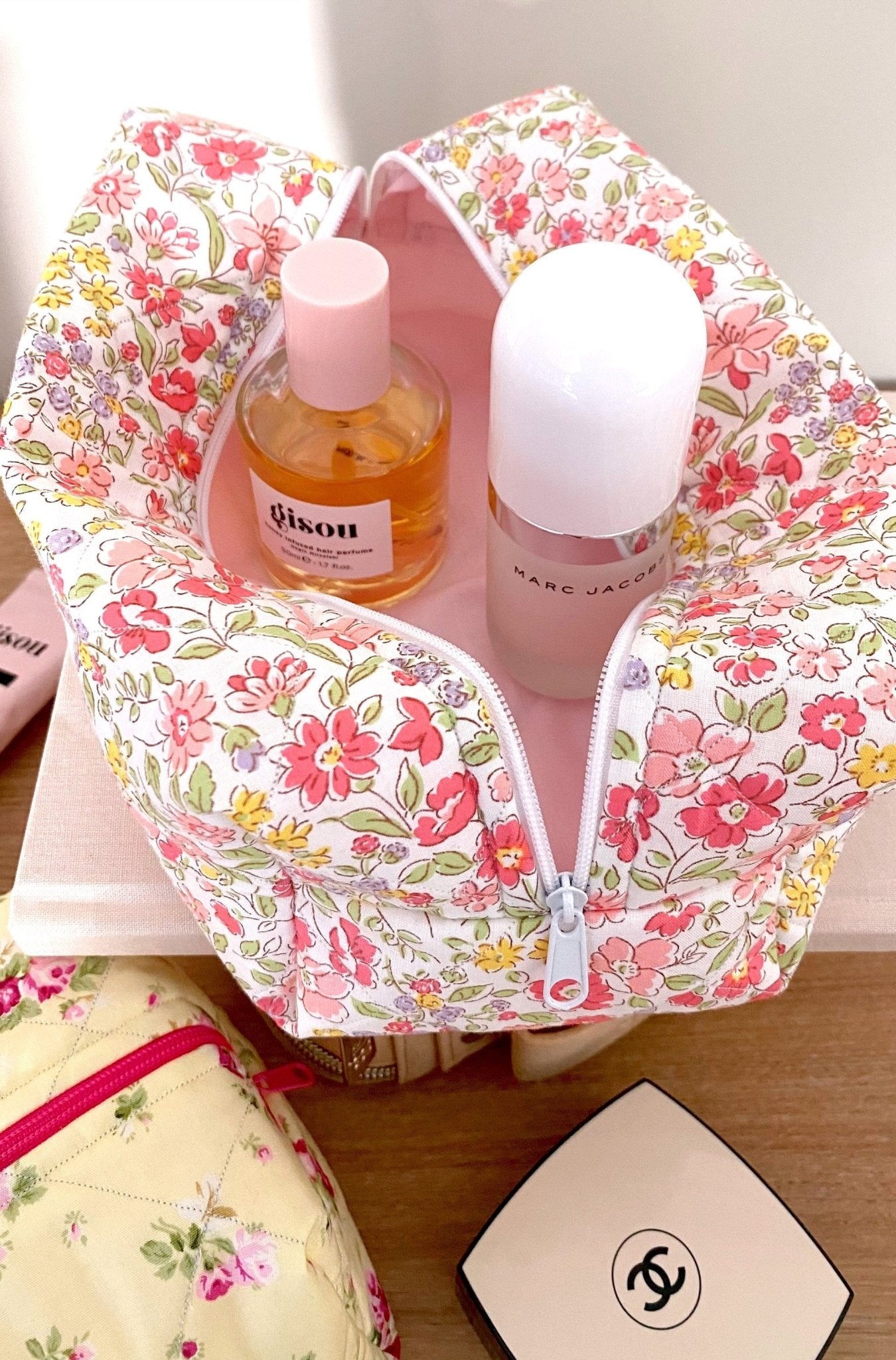 Red floral toiletry organizer pouch with bottles and white pump tops inside