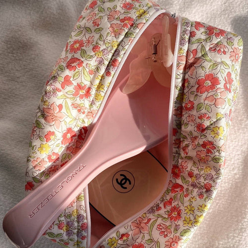 Floral zip pouch open with pink interior, close-up of zipper and bottle tops