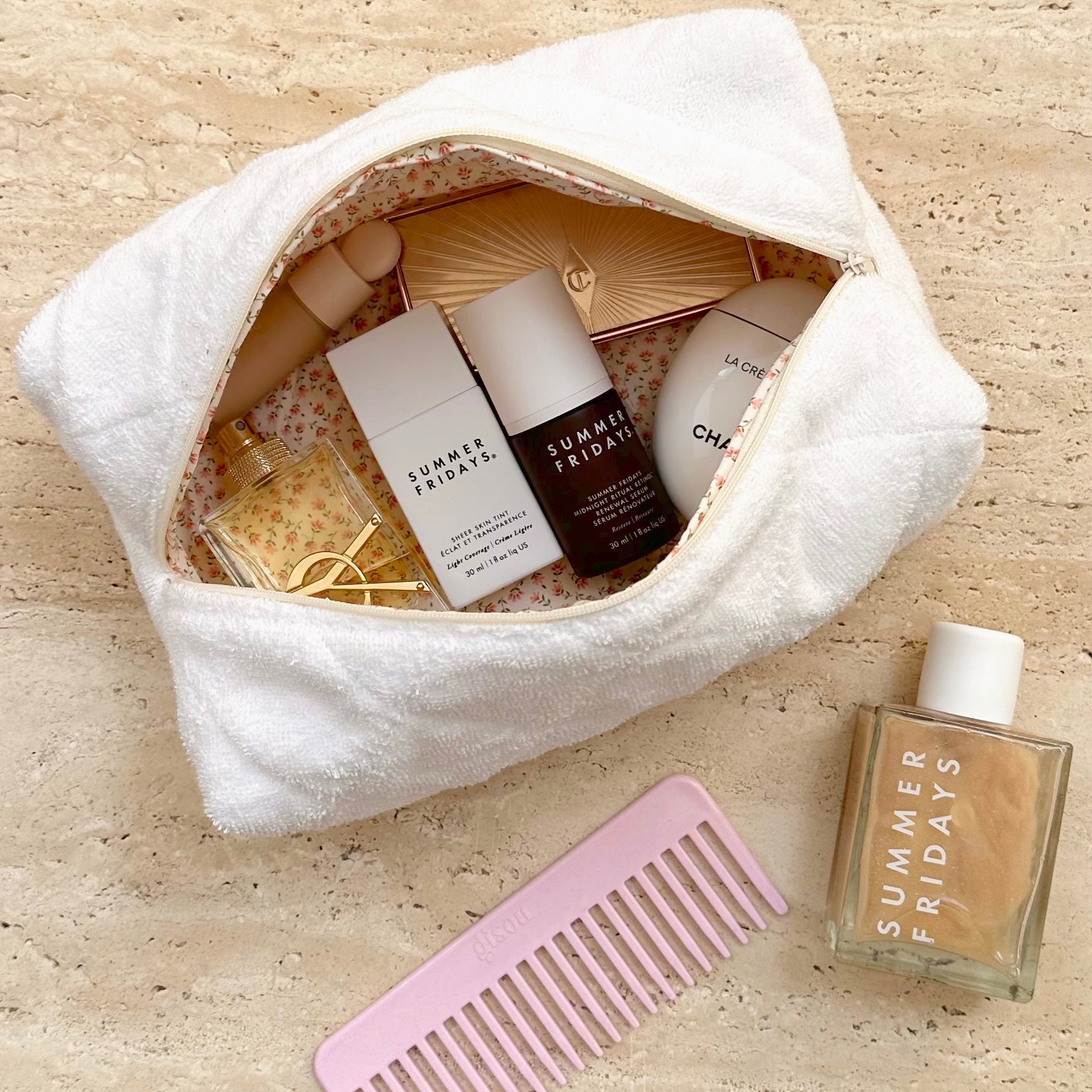White terrycloth pouch with zip, ditzy floral lining and visible skincare items inside
