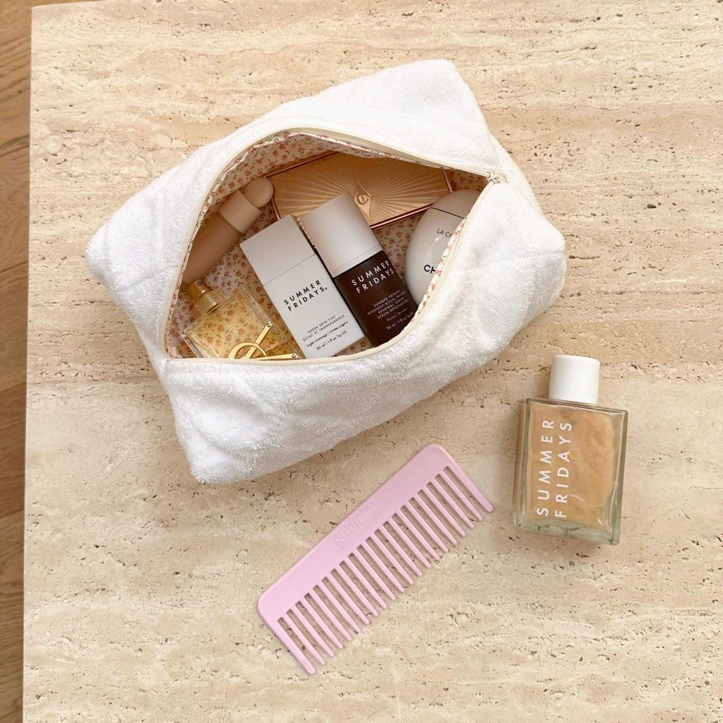 Open white terrycloth pouch with zip; ditzy floral lining and toiletries arranged inside