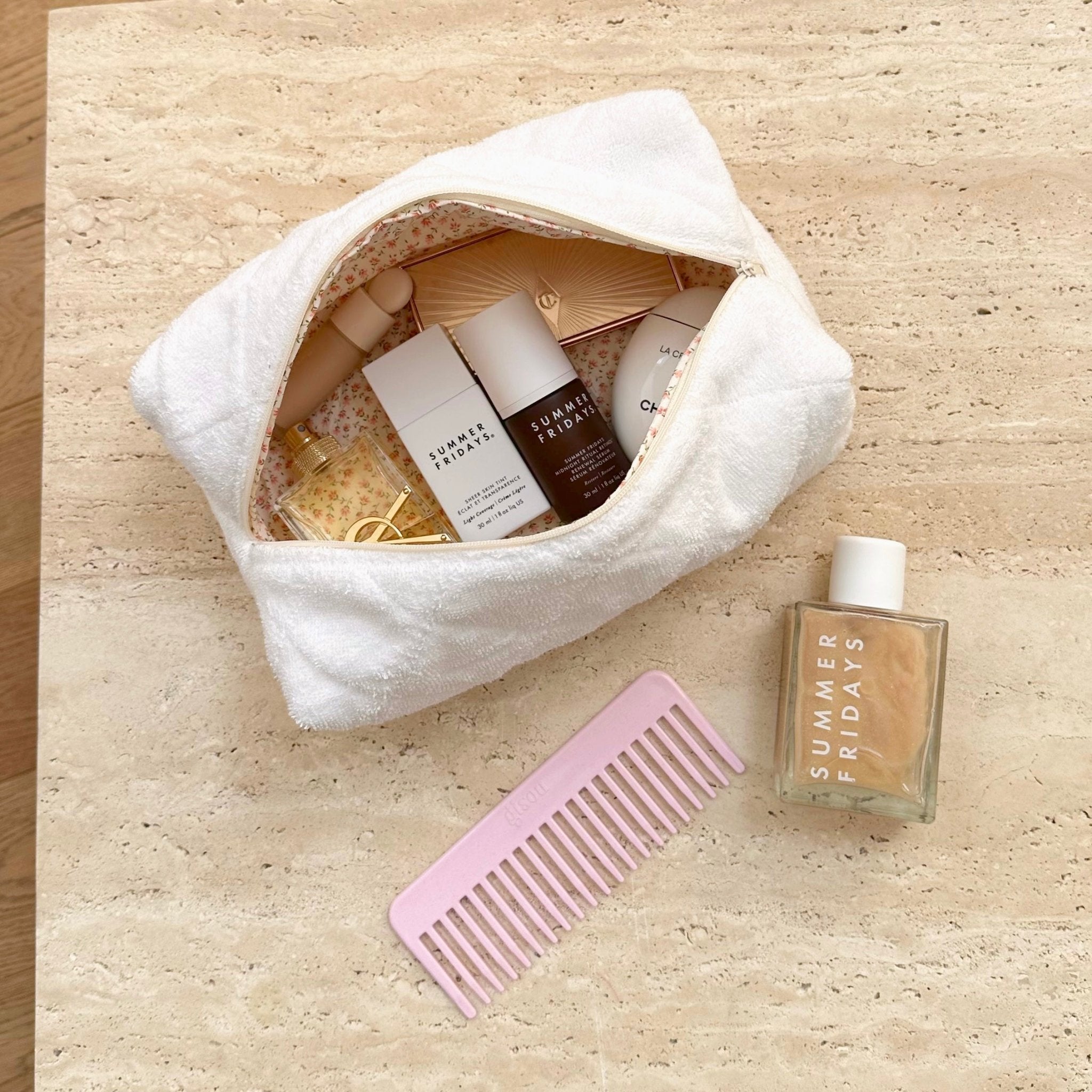 Open white terrycloth pouch with zip; ditzy floral lining and toiletries arranged inside