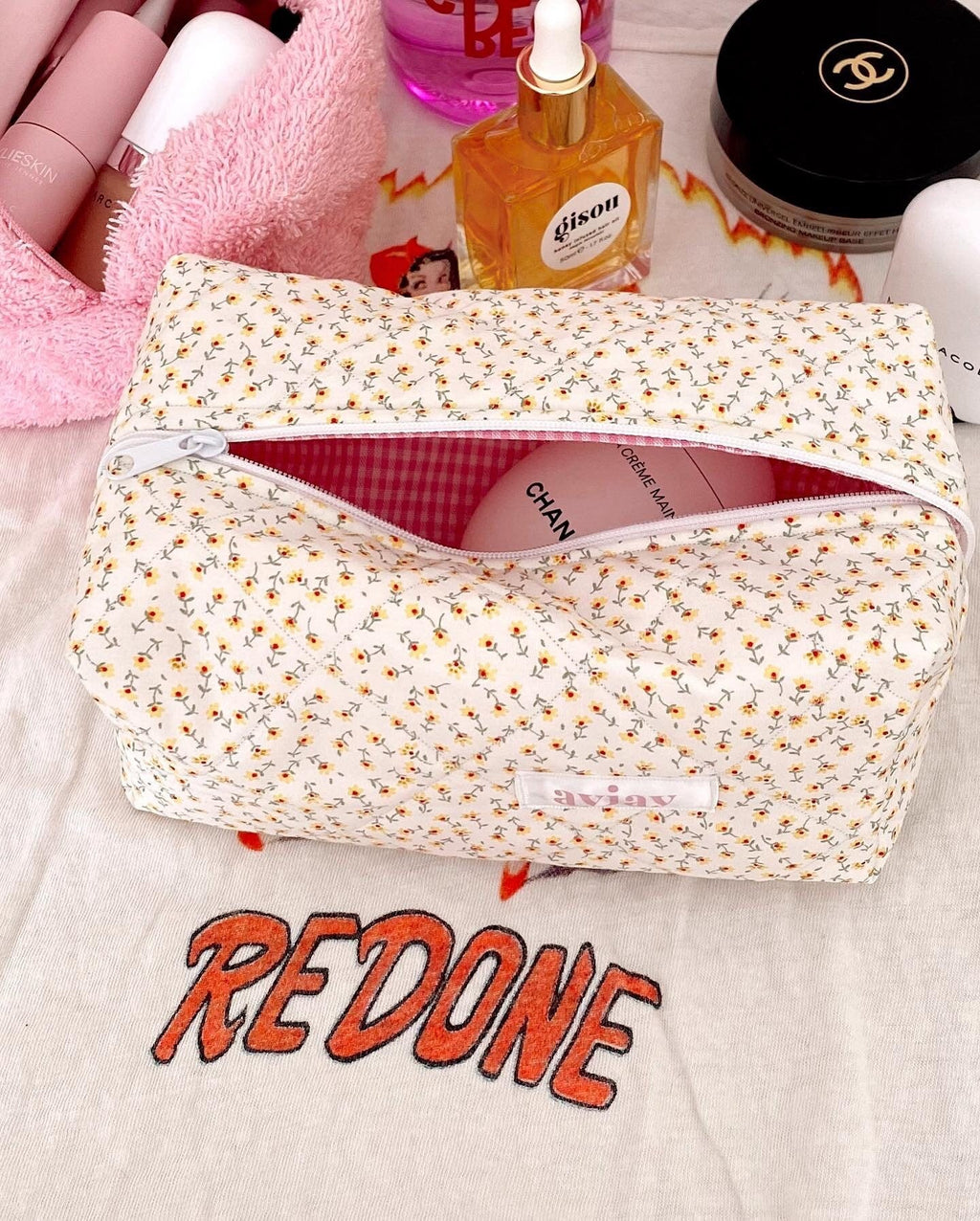 Side view of cream floral zipper pouch with pink gingham interior and top flap
